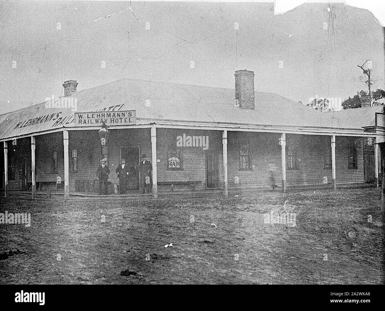 Negative - Three Men Outside W. Lehrmann's Railway Hotel, Victoria (?), circa 1895, Three men outside W. Lehrmann's Railway Hotel. The hotel is a single-story timber building with a veranda. There are three chimneys visible in the image Stock Photo