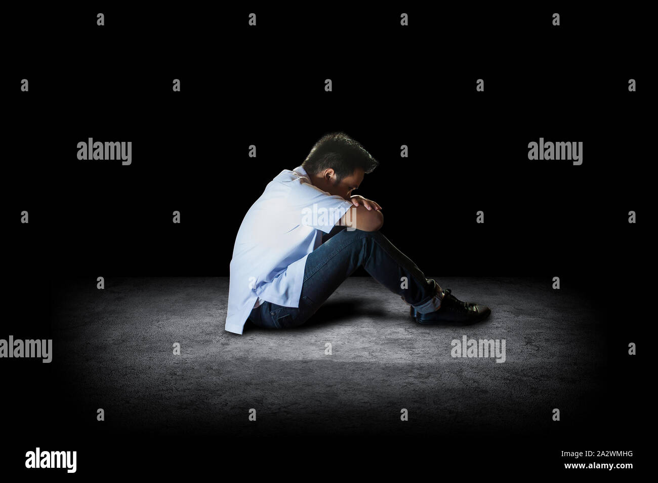 A depressed student sitting on a floor with his head down crying. Depressed school boy in side view Stock Photo - Alamy