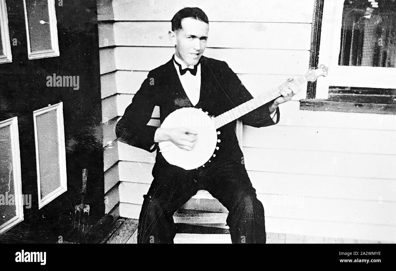 Negative - Man Playing a Banjo, Lake Goldsmith, Victoria, 1935, Man in a dinner jacket and black tie playing the banjo. There is a door on the left Stock Photo
