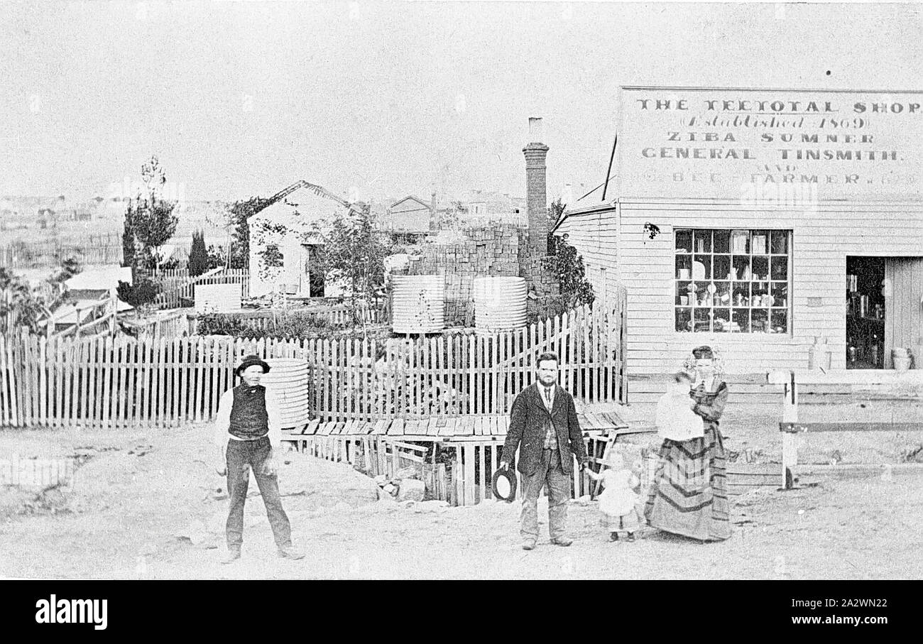Negative - Sumner Family Outside 'The Teetotal Shop', Ballarat, Victoria, 1875, The Sumner family outside 'The Teetotal Shop. Established 1869, Ziba Sumner, General Tinsmith.'. There are water tanks and a wooden bridge behind the family Stock Photo
