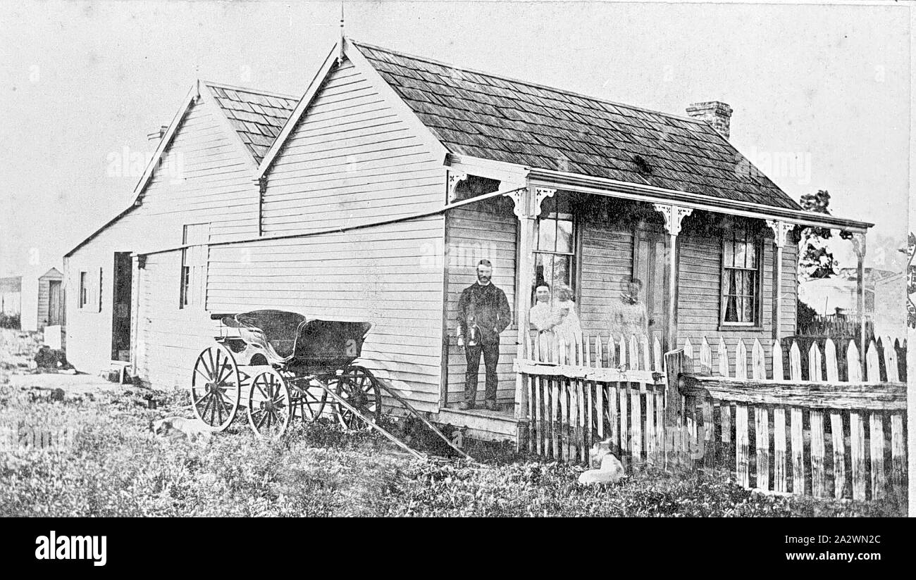 Negative - Family Standing on the Verandah of their Home, Majorca (?), Victoria, circa 1880, A family standing on the verandah of their home. A buggy is parked at the side of the house. There is a shingle roof and a drain pipe runs from the guttering at the front of the house to the rear (but not, apparently, to a water tank unless the tank is sunk in the ground Stock Photo