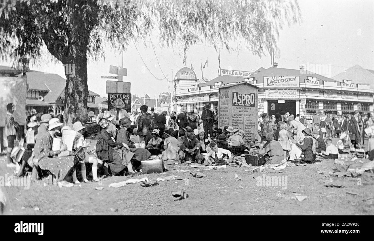 Negative - Sydney, New South Wales, 1933, People on the grass at Sydney Royal Agricultural Show. Some are resting and some picnicking. There is a considerable amount of litter on the grass. There are many advertising signs in the background: Nestle, Aspro, Lactogen, Peters etc Stock Photo