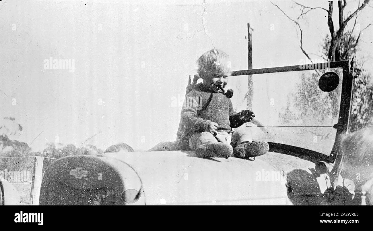 Negative - Manangatang, Victoria, circa 1930, A toddler sitting on the bonnet of a Chevrolet motor car. He has a pipe in his mouth Stock Photo