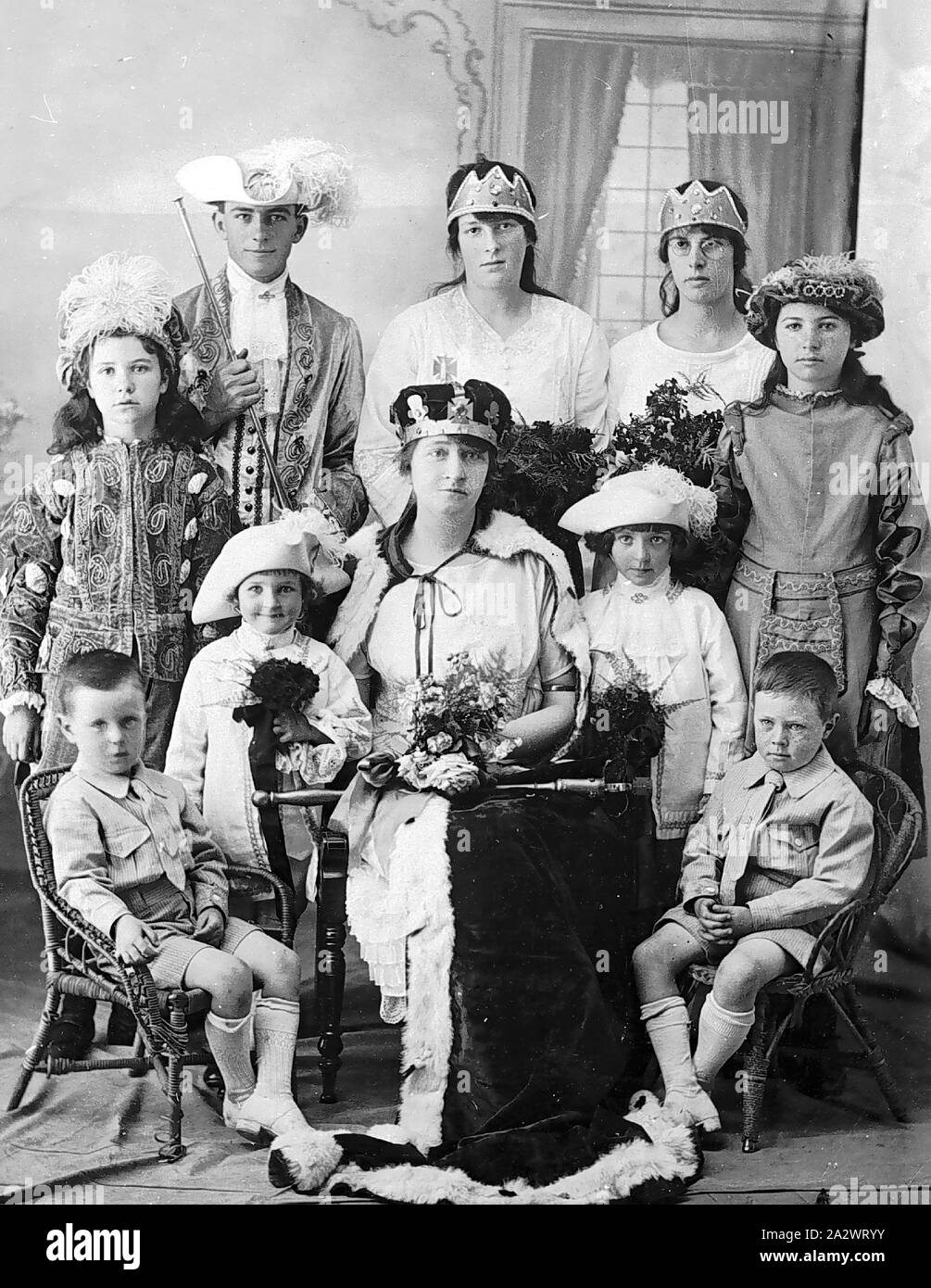 Negative - Victoria, pre 1930, A group, largely in fancy dress (the two small boys in the front are wearing street clothes). The woman in the centre is dressed as a queen with a crown, robe and sceptre Stock Photo