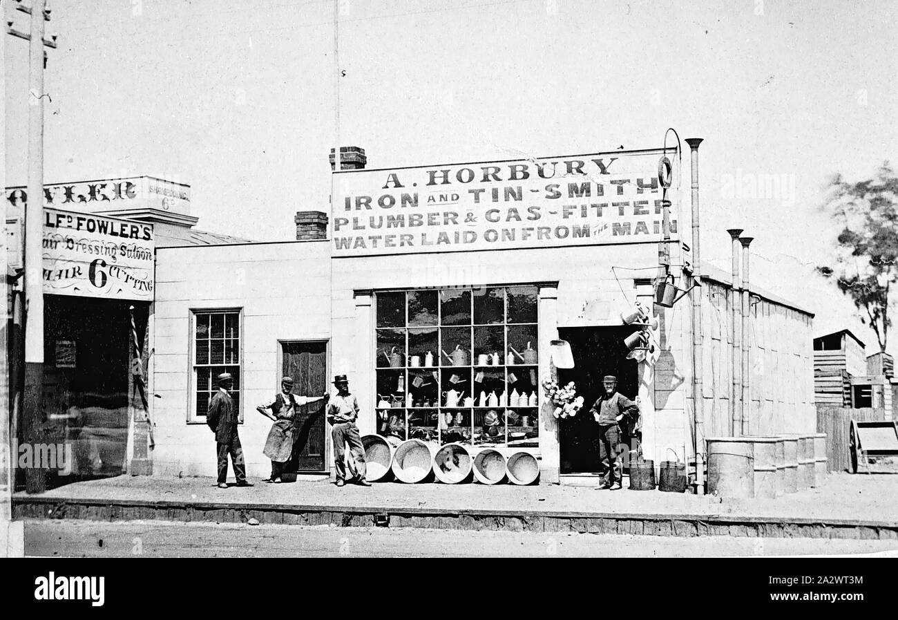 Negative - A. Horbury's Shop, Bendigo, Victoria, 1863, Four men standing outside the shop of A. Horbury. The sign above the shop reads 'A. Horbury, iron and Tin-Smith, Plumber & Gas Fitter, water laid on from the main.' On the left is Alfred Fowler's Hairdressing Salon Stock Photo