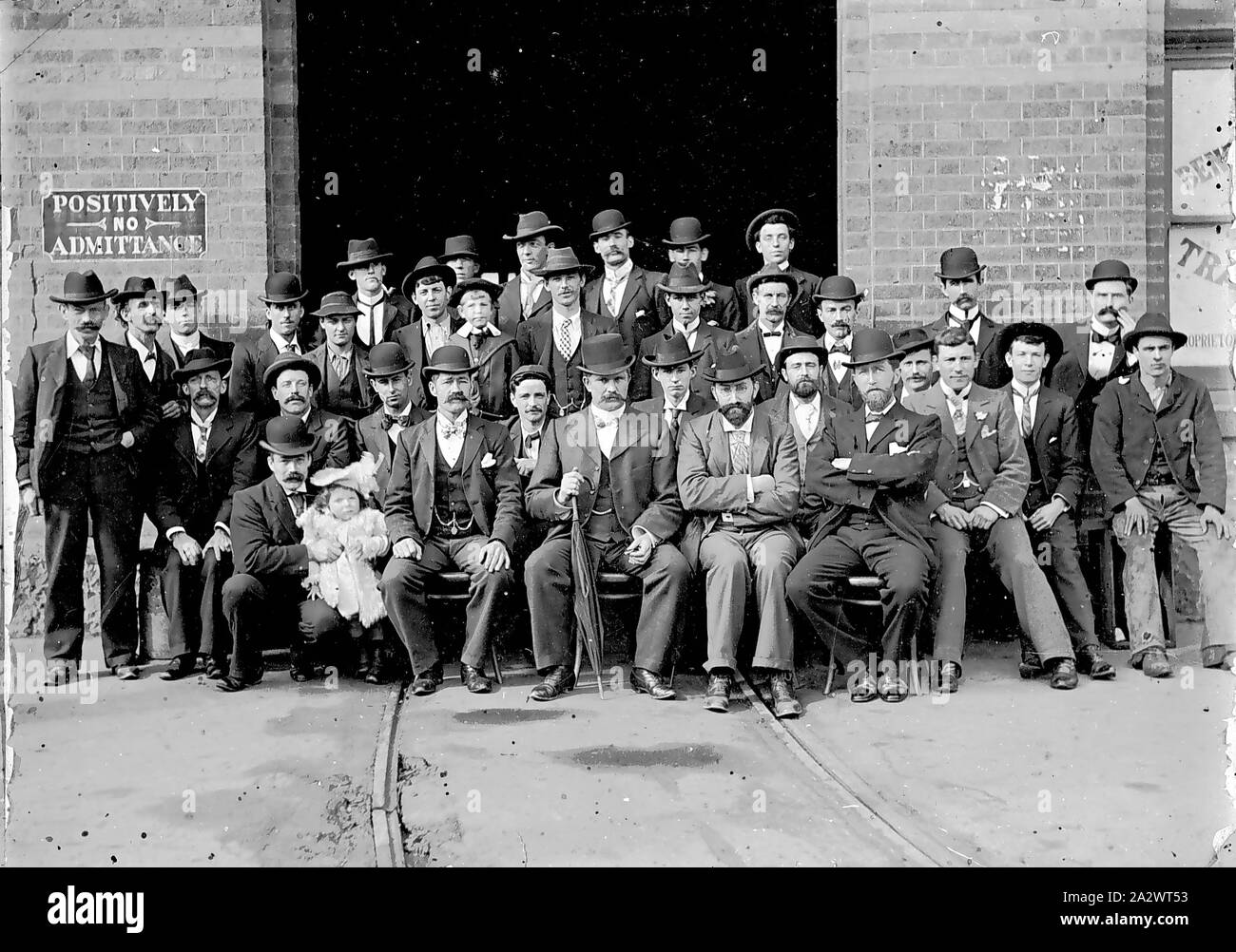 Negative - Bendigo, Victoria, circa 1905, A group of men at a tram entrance of the Bendigo Tramways. The men are all well-dressed and one holds a baby on his knee Stock Photo