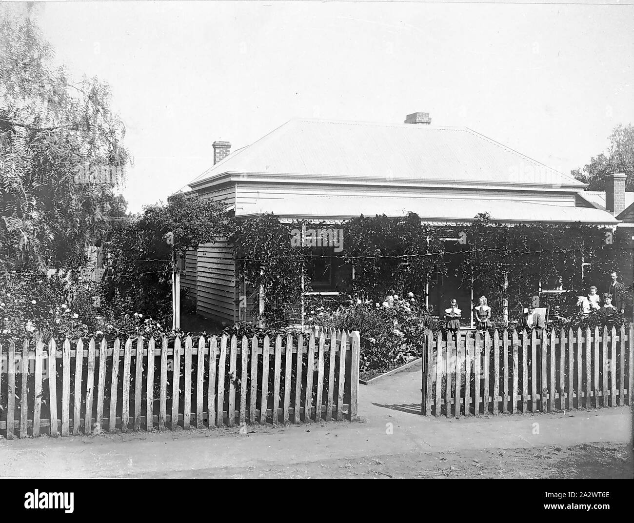 Negative - Bode Family in Front of their Home, Kerang, Victoria, circa 1909, Black and white image of the Bode family in front of their home in Kerang, Victoria, about 1909-1910. The family is pictured, left to right: standing on the path Esther May Bode and Edith Lavinia Bode; their mother Mary Jane Bode (nee Morrison) seated; Leslie Bode on rocking horse; Victor Bode; and their father Albert Bode Stock Photo