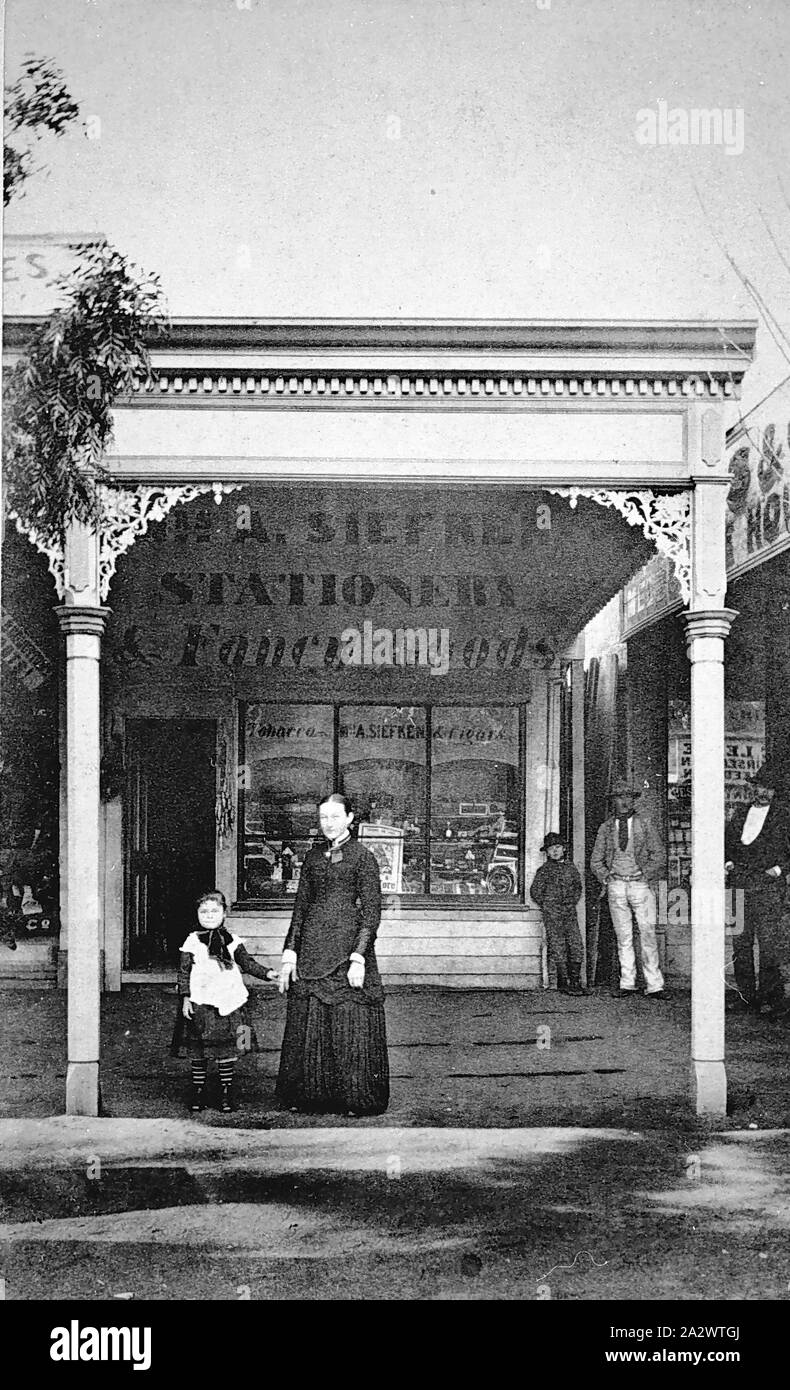 Negative - Echuca, Victoria, circa 1875, A woman and child in front of A. Siefker, Stationer & Fancy Goods. There are two men and a young boy in the background Stock Photo