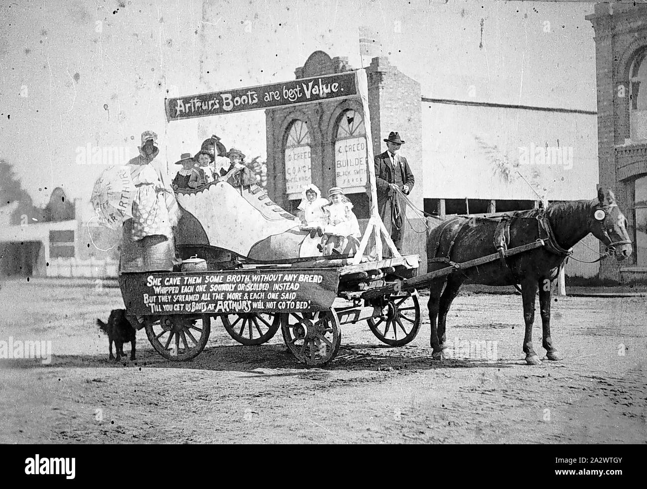 Negative - Bairnsdale, Victoria, circa 1900, A horse float in a carnival procession. The theme of the float is 'The old woman who lived in a shoe' and a sign on the side reads: She gave them some broth without any bread/ whipped each one soundly or scolded instead/ but they yelled all the more and each one said/ 'till you get us boots at Arthur's we'll not go to bed. A sign above the float reads: Arthur's boots are best value Stock Photo