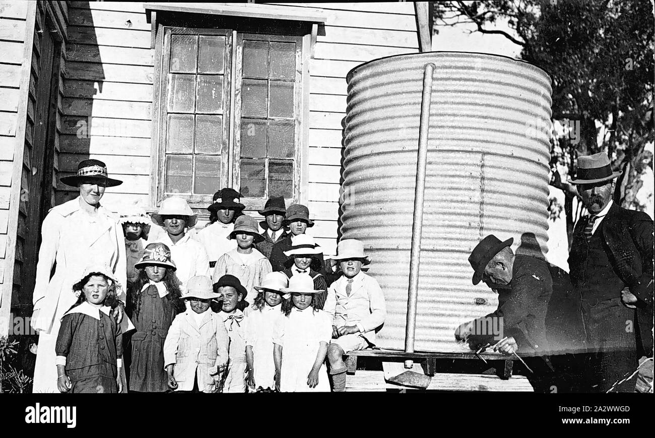 Negative - Berrimull, Victoria, 1915, A group of students and a female teacher being photographed beside the corrugated iron water tank outside a the Berrimal State School Stock Photo
