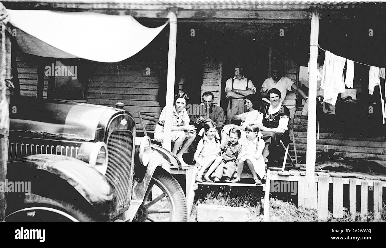 Negative - Errinundra, Victoria, circa 1930, A family group on a verandah. There is a canvas awning over a Chevrolet car parked at the front of the house and clothes drying on a line on the verandah Stock Photo