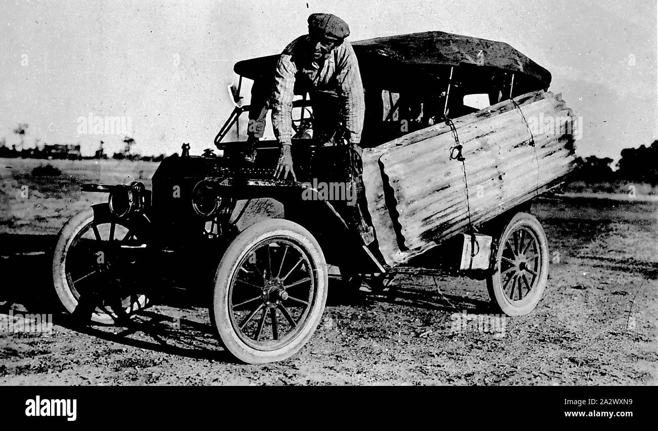 Negative - Outback Motor Car Trip, Northern Territory (?), circa 1920, A Model T Ford car with the driver adjusting corrugated iron sheeting strapped to the side of the car Stock Photo