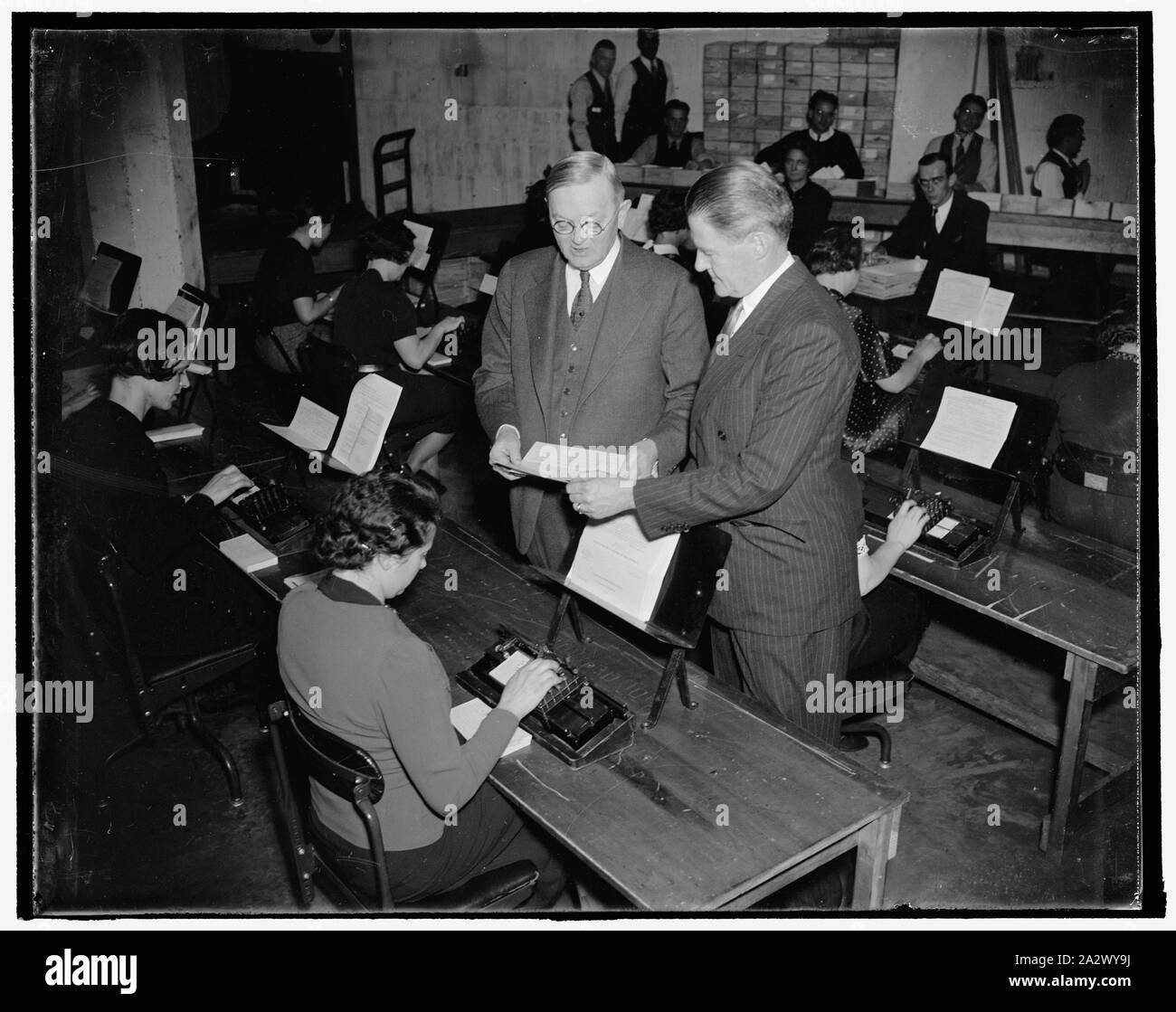 Responsible for unemployment census. Washington, D.C., Nov. 24. William L. Austin (left) Director of the U.S. Census Bureau and whose workers are tabulating the returns from the unemployment questionnaires, describes to Unemployment Census Director John D. Biggers the working of the special tabulating machine used to count the unemployed noses. Work of counting the unemployed returns was begun in the Capital today. 11/24/37 Stock Photo