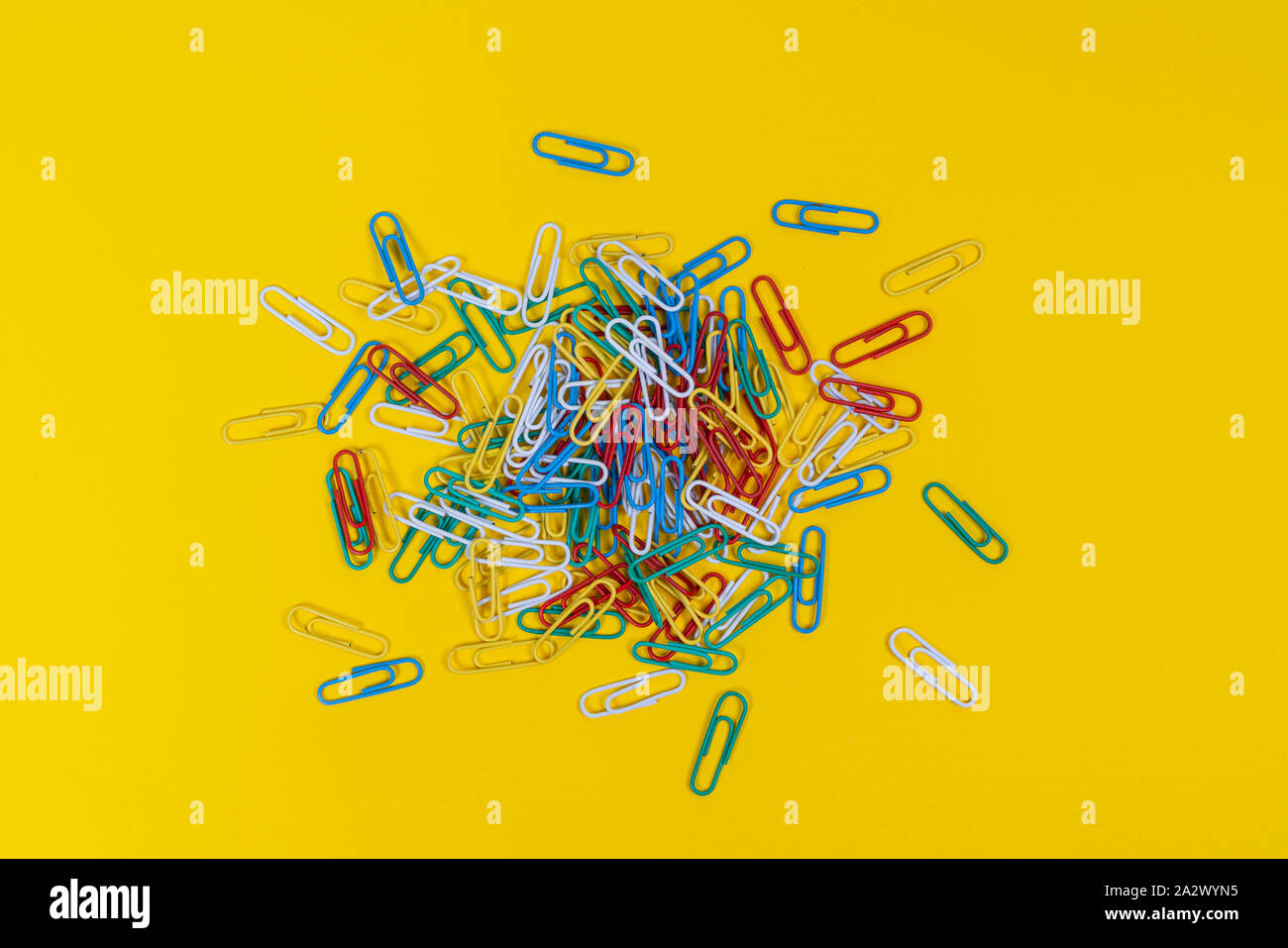a pile of colored paper clips scattered on a yellow surface Stock Photo ...