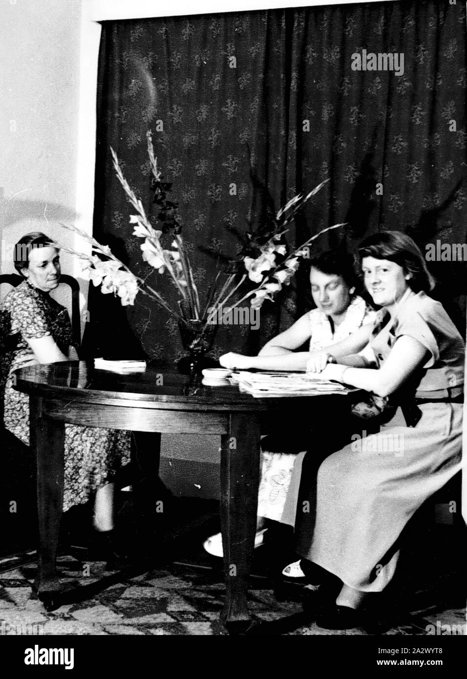 Negative - Graham Family in Dining Room, Hartwell, Victoria, 1948, Black and white negative of the Graham family in the dining room of their home in Hartwell, 1948. At left is Mrs Henrietta Graham, nee Mitchell, with her daughters - in the middle is Ruth Graham, and at right is Mary Graham Stock Photo