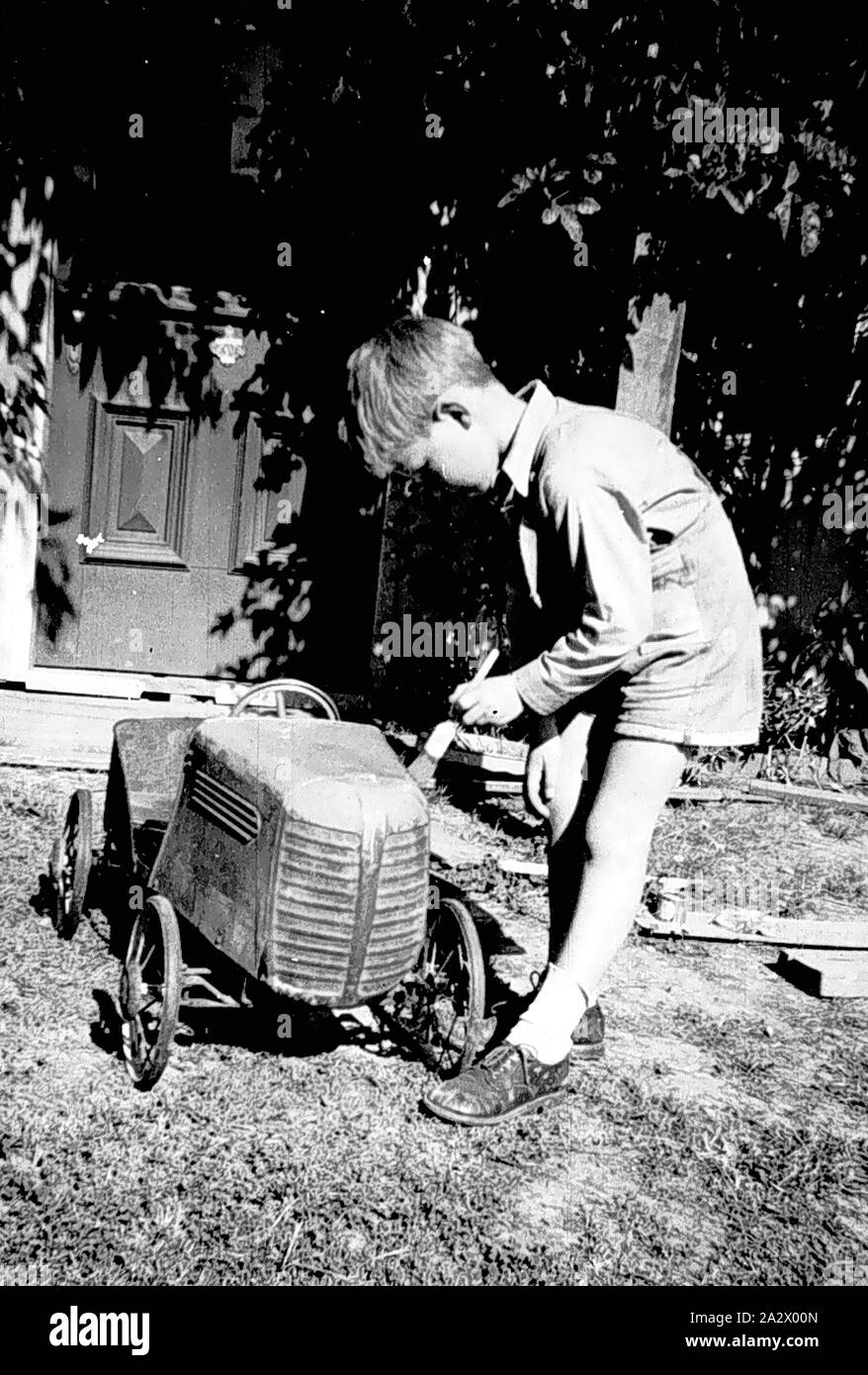 Negative - Greensborough, Victoria, 1959, A boy painting a pedal car Stock Photo