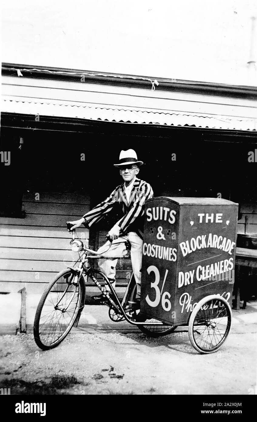 Negative - Man on Advertising Bicycle, Ballarat, Victoria, 1938, A man on a bicycle which has a side car. The sidecar advertises 'the Block Arcade Dry Cleaners' and 'Suits & Costumes 3/6'. The man is wearing a striped blazer Stock Photo