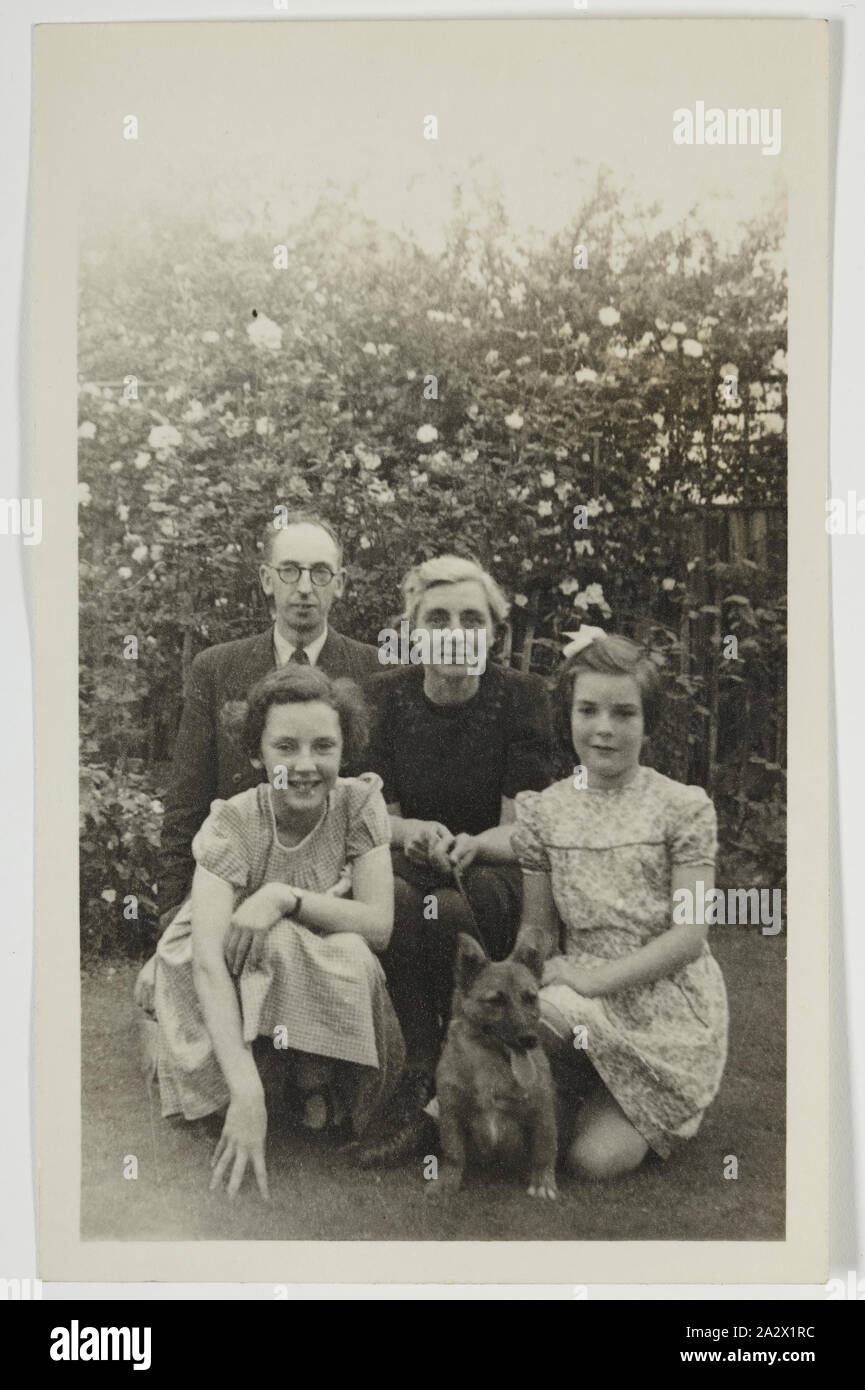 Photograph - Palmer Family in Garden, Iver, England, circa 1947, Black and white photograph George and Gertrude Palmer, their daughters Shirley and Lesley, and their dog Robbie, in England around 1947. It was probably taken at George's sister's house in Iver, Buckinghamshire by George's brother-in-law David Roberts. It was brought to Australia by George Palmer when he migrated to Australia from England with his wife Gertrude and their two daughters, Shirley Stock Photo