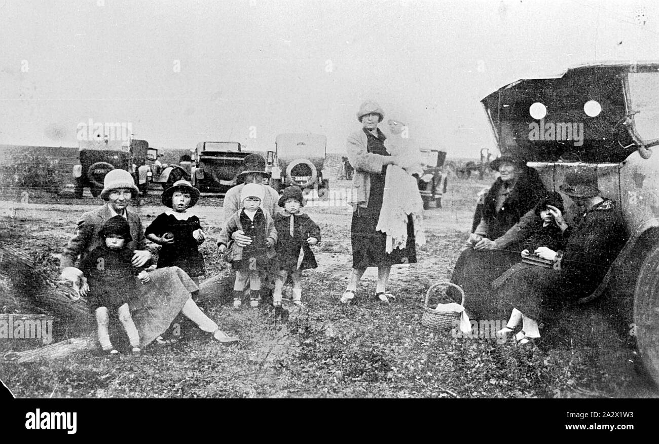 Negative - Farming Families Posed With their Cars During the Visit of the Better Farming Train, Underbool, Victoria, 1926, Farming families posed with their cars during the visit of the Better Farming Train. Five women and six children are sitting and standing near a car. A basket at their feet suggests they may have been having a picnic Stock Photo