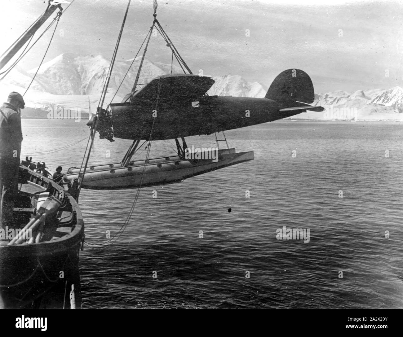 Photograph - Lowering Lockheed Vega Float Plane from Ship, Wilkins Hearst Antarctic Expedition, by George Rayner, Port Lockroy, Antarctica, circa 1929, PHOTOGRAPH; UNLOADING AEROPLANE FITTED WITH FLOATS FROM SHIP, CIRCA 1929. AEROPLANE MARKED WILKINS HEARST ANTARCTIC EXPEDITION AND LOCKHEED AIRCRAFT CO. LOS ANGELES U.S.A. AND VEGA X3903. PHOTOGRAPH PROBABLY TAKEN BY GEORGE RAYNER IN ANTARCTICA Stock Photo