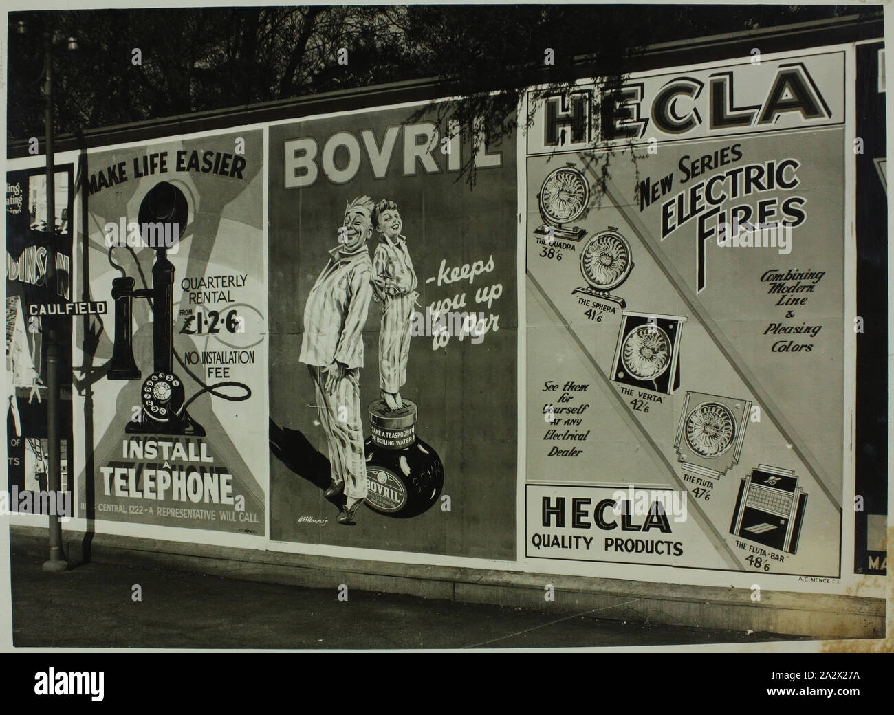 Photograph - Billboard Posters featuring Hecla Electrics Pty Ltd, 'Electric Fires', Caulfield, circa 1940, Black and white photograph of billboard posters on the platform at Caulfield Railway Station in Melbourne, circa 1940. The posters are advertising telephone installation, Bovril, and Hecla Electrics Pty Ltd new series of 'electric fires'. The models of electric fires featured are 'Quadra', 'Sphera', 'Verta', 'Fluta' and the 'Fluta-Bar', and prices are included in the poster. The designs mark Stock Photo