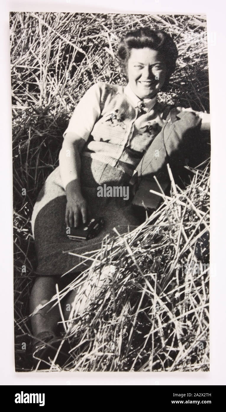 Photograph - Esma Banner, circa 1950, Photograph of Esma Banner holding a camera and sitting in what appears to be a bundle of hay. Esma Banner worked in displaced persons' camps in the US Zone of Germany after World War II as an employment and welfare officer for the United Nations Relief and Rehabilitation Administration (UNRRA) and the International Refugee Organization (IRO), from 1945 to 1951. Esma was one of 39 Australians who Stock Photo