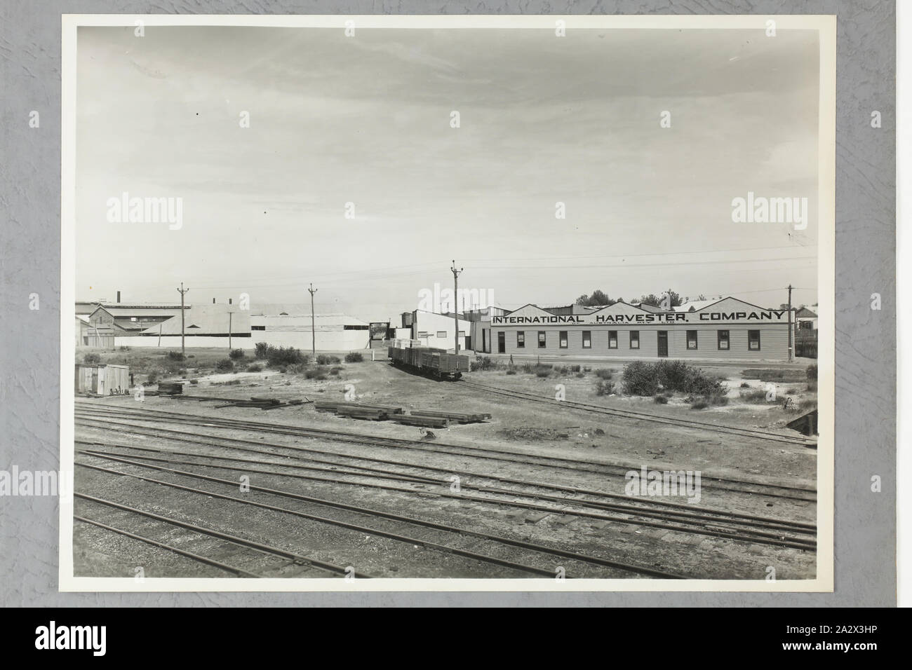 Photograph - International Harvester, Factory Exterior & Railway Yard, Perth, circa 1947, One of two black and white photographs attached to an album page. The page is one of 28 that previously made up a photograph album containing black & white photographs of the International Harvester Company's state branch offices and showrooms throughout Australia. Part of a large collection of glass plate and film negatives, transparencies, photo albums, product catalogues, videos Stock Photo