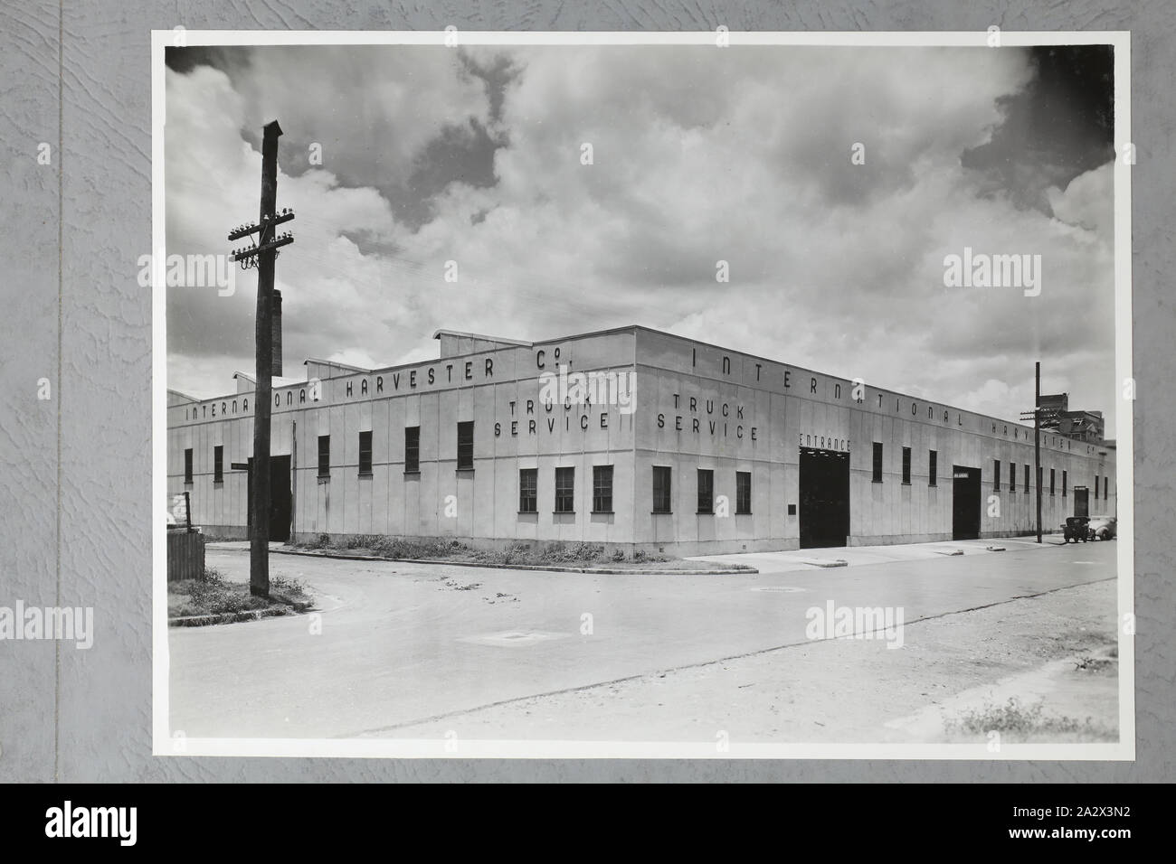 Photograph - International Harvester, Truck Service Workshop Exterior, Brisbane, 09 Jan 1947, One of four black and white photographs attached to an album page. The page is one of 28 that previously made up a photograph album containing black & white photographs of the International Harvester Company's state branch offices and showrooms throughout Australia. Part of a large collection of glass plate and film negatives, transparencies, photo albums, product catalogues, videos Stock Photo