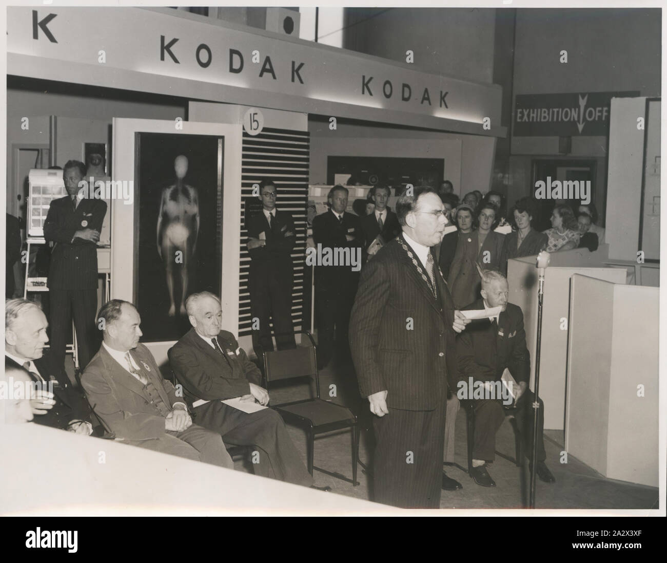 Photograph, Presentation in Front of Kodak Exhibition Stand, circa 1940s, Black and white photograph of a formal presentation given in front of a Kodak Australasia Pty Ltd exhibition stand, circa 1940s. This photograph is part of the Kodak collection of products, promotional materials, photographs and working life artefacts, when the Melbourne manufacturing plant at Coburg closed down. manufactured and distributed a wide Stock Photo