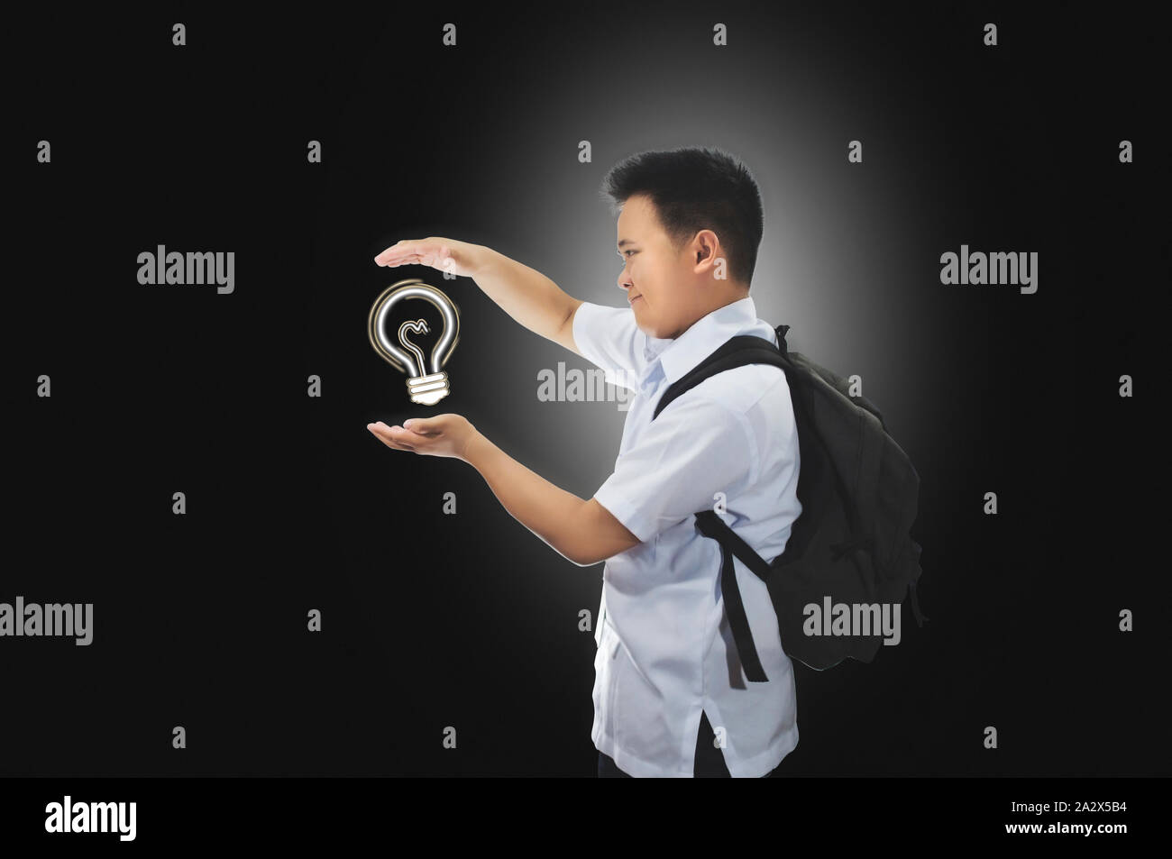 Happy young male student in school uniform with back pack beholding an idea. Light bulb idea concept. Success, creative, and idea concept Stock Photo