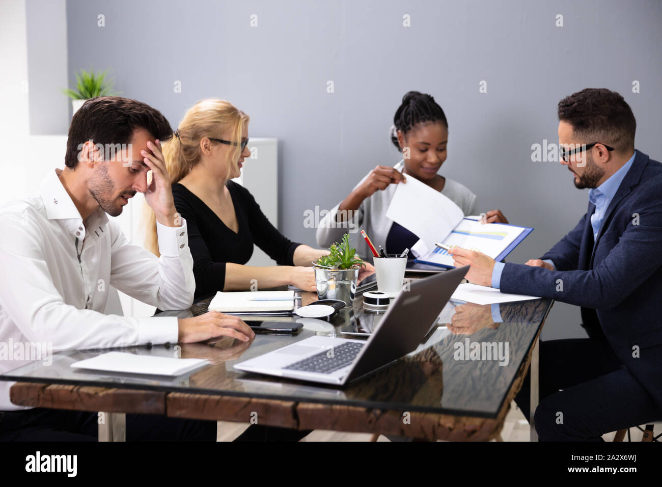 Bored Male Manger Sitting With His Colleagues Giving Presentation In Meeting At Office Stock Photo
