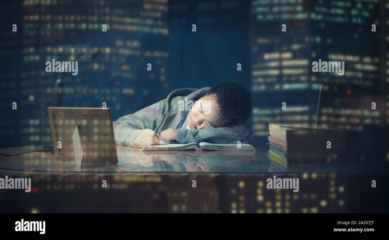Male student fell to sleep in studying late night while studying for a test. School boy lazy to study the test for tomorrow. Cramming exam. Stock Photo