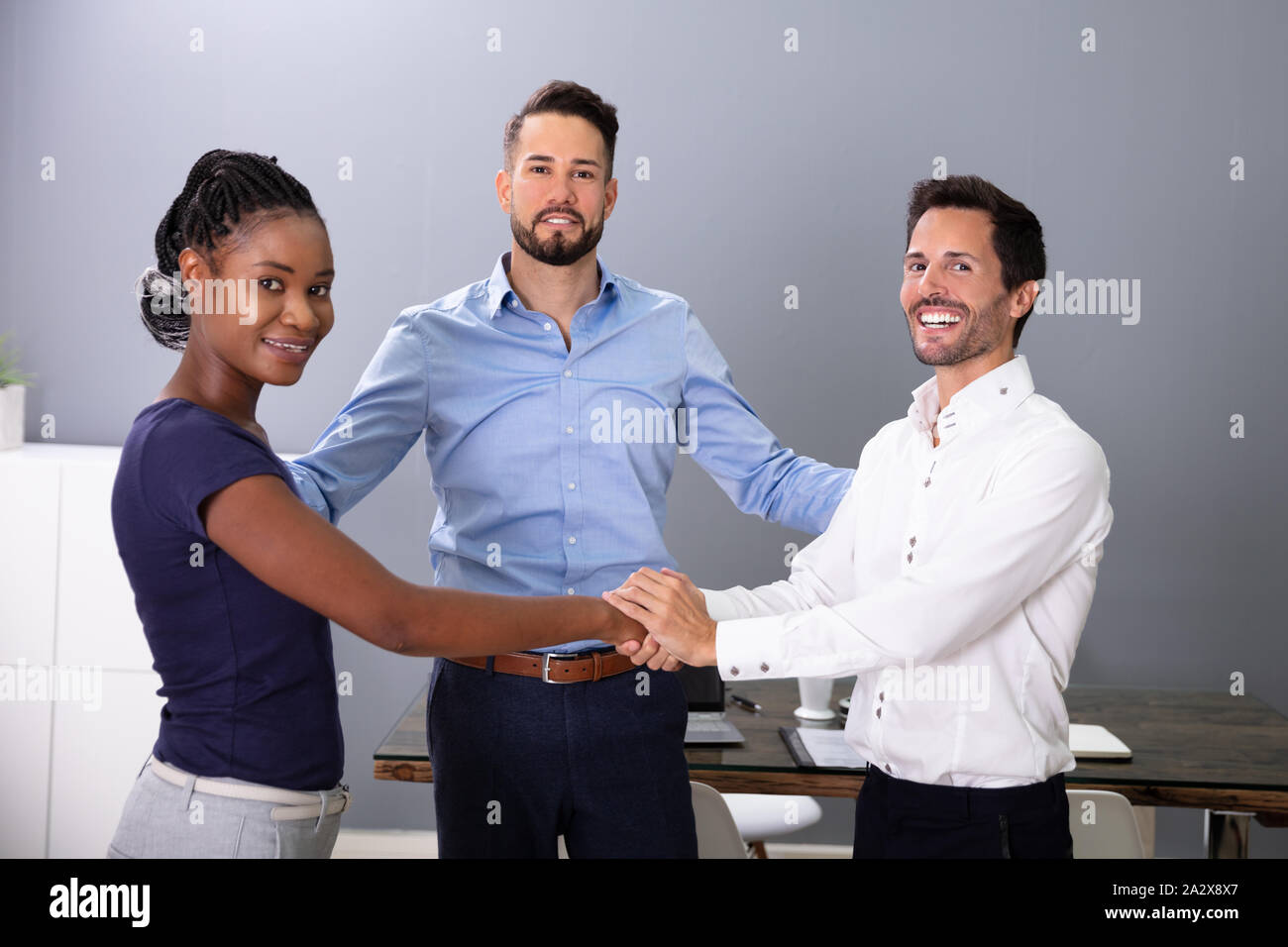 Man Looking At Happy Business People Shaking Hands In Meeting Room Stock Photo