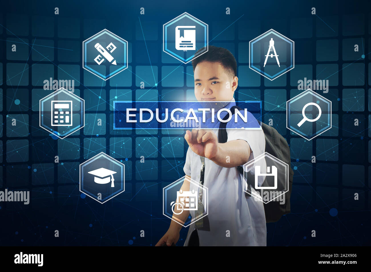 Student touching virtual screen.  Young school boy touching a hologram display screen with labelled Education with study materials icons. Stock Photo