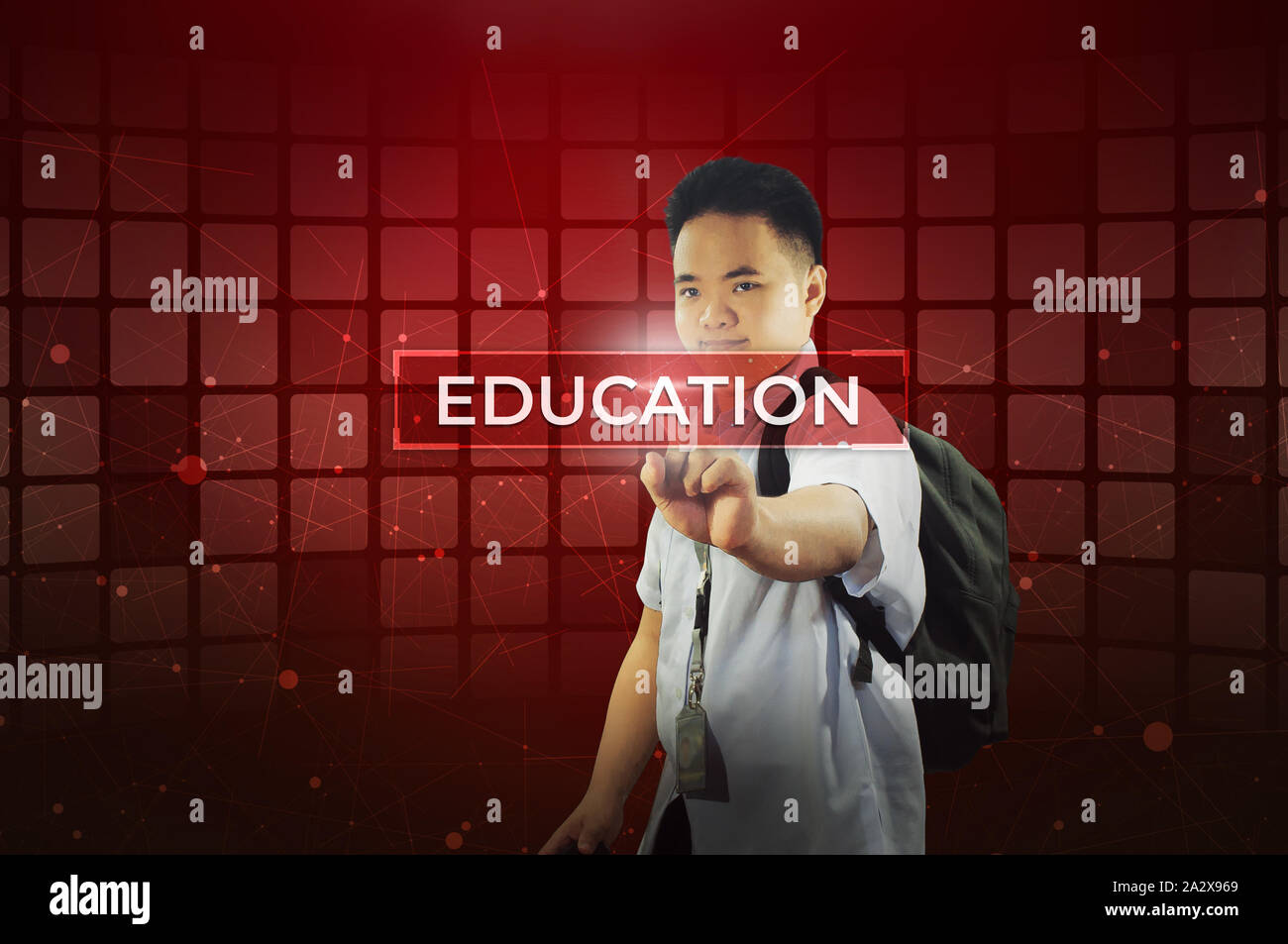 Student touching virtual screen.  Young school boy touching a hologram display screen with labelled Education with study materials icons. Stock Photo