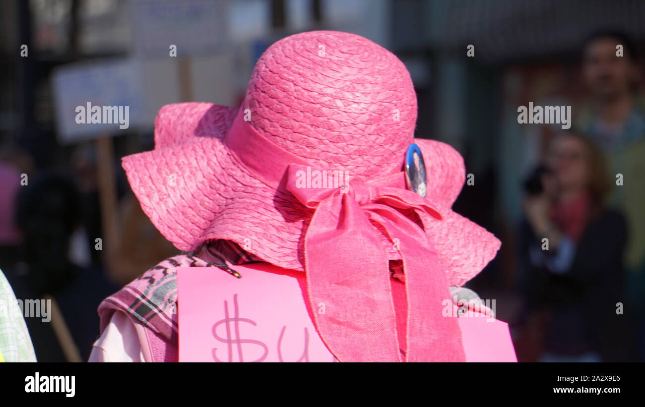 Protester wearing a straw pink hat with pink ribbon at the 2019 Women's March, San Francisco, USA. Protesters and photographer are in the background. Stock Photo