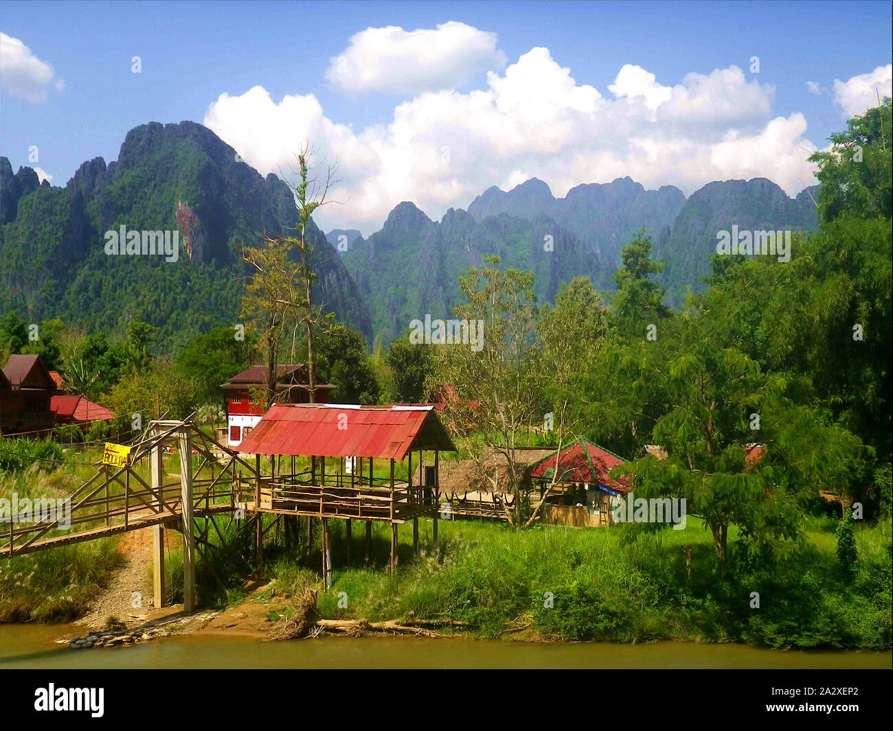 Village in Laos, Small Village Community, Houses Mostly Three-Storey, Houses Covered with Grass Mats or Corrugated Iron, Wooden Bridge over the River Stock Photo
