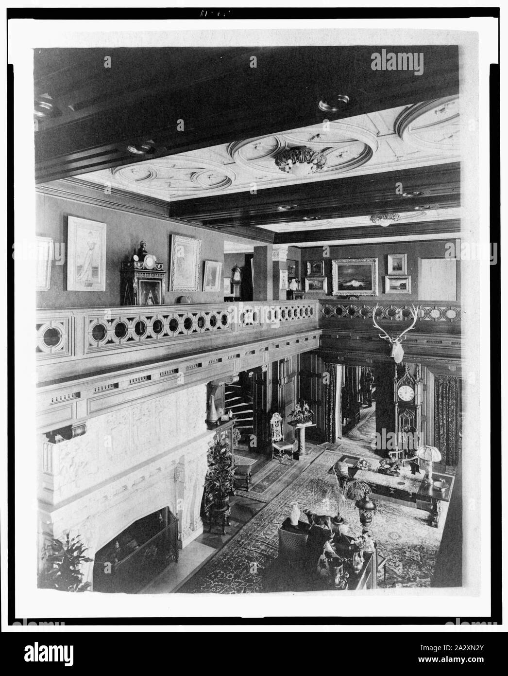 Room with balcony, paintings, fireplace, grandfather clock, and elk head, in home of Edmund Cogswell Converse, Greenwich, Connecticut Stock Photo