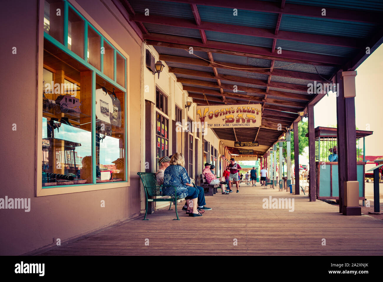 Low angle view of Tourists relaxing and strolling along the wooden plank sidewalks of the storefronts under a wooden portico in the historical old wes Stock Photo