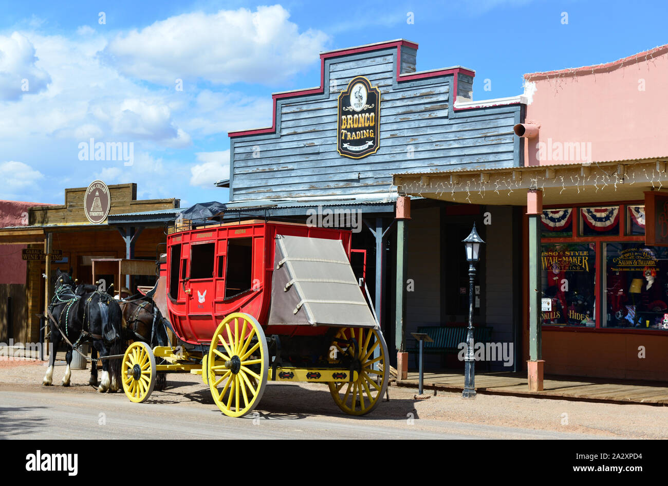 A red stagecoach with yellow wheels awaits passengers with two resting horses alongside storefronts in   historical Tombstone, AZ, USA Stock Photo