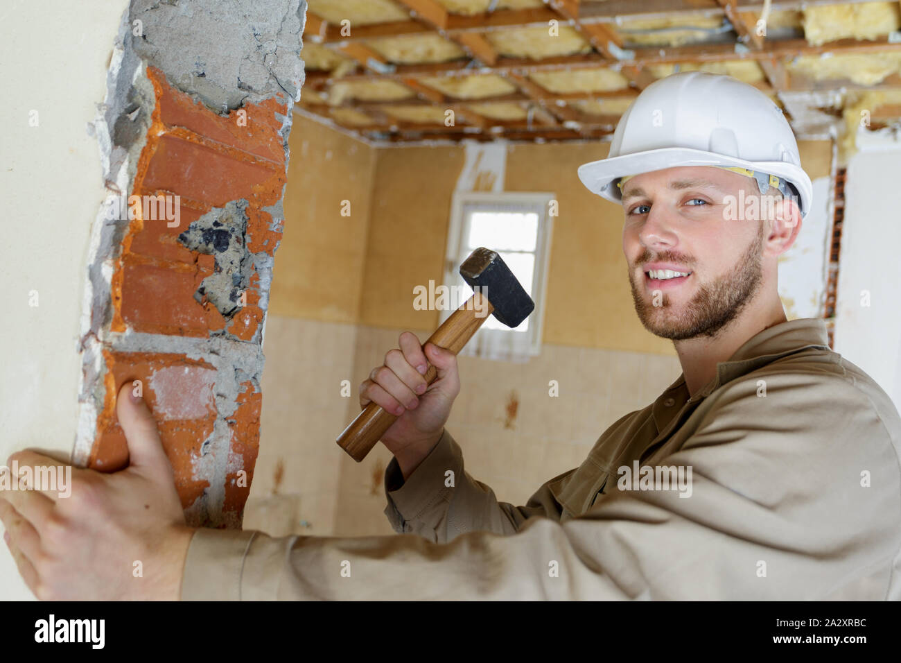 young builder using a hammer to remove walls plaster Stock Photo Alamy