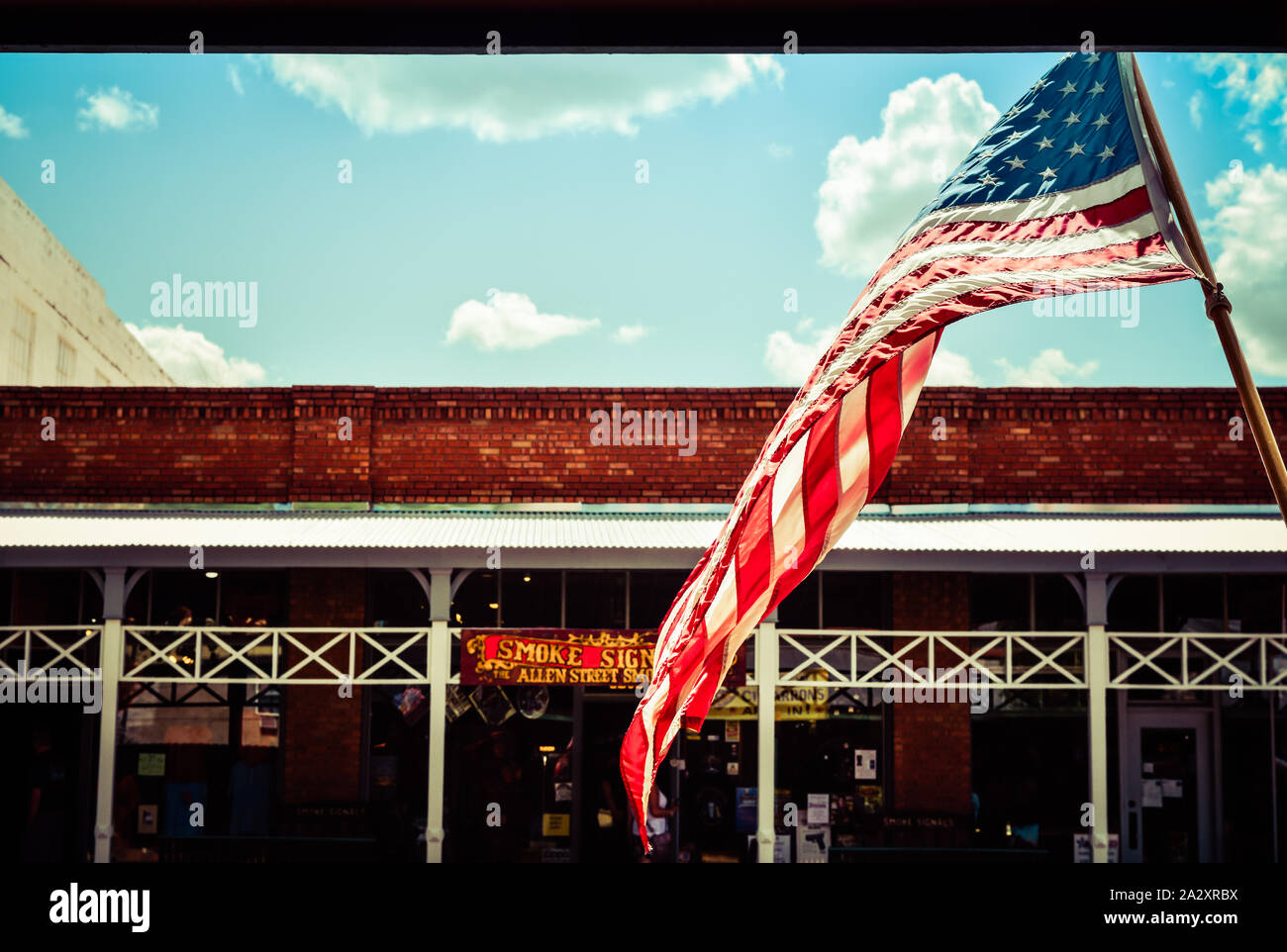 Large American flag flies over old brick buildings along the storefronts in the legendary and historical small town America West site of Tombstone, AZ Stock Photo
