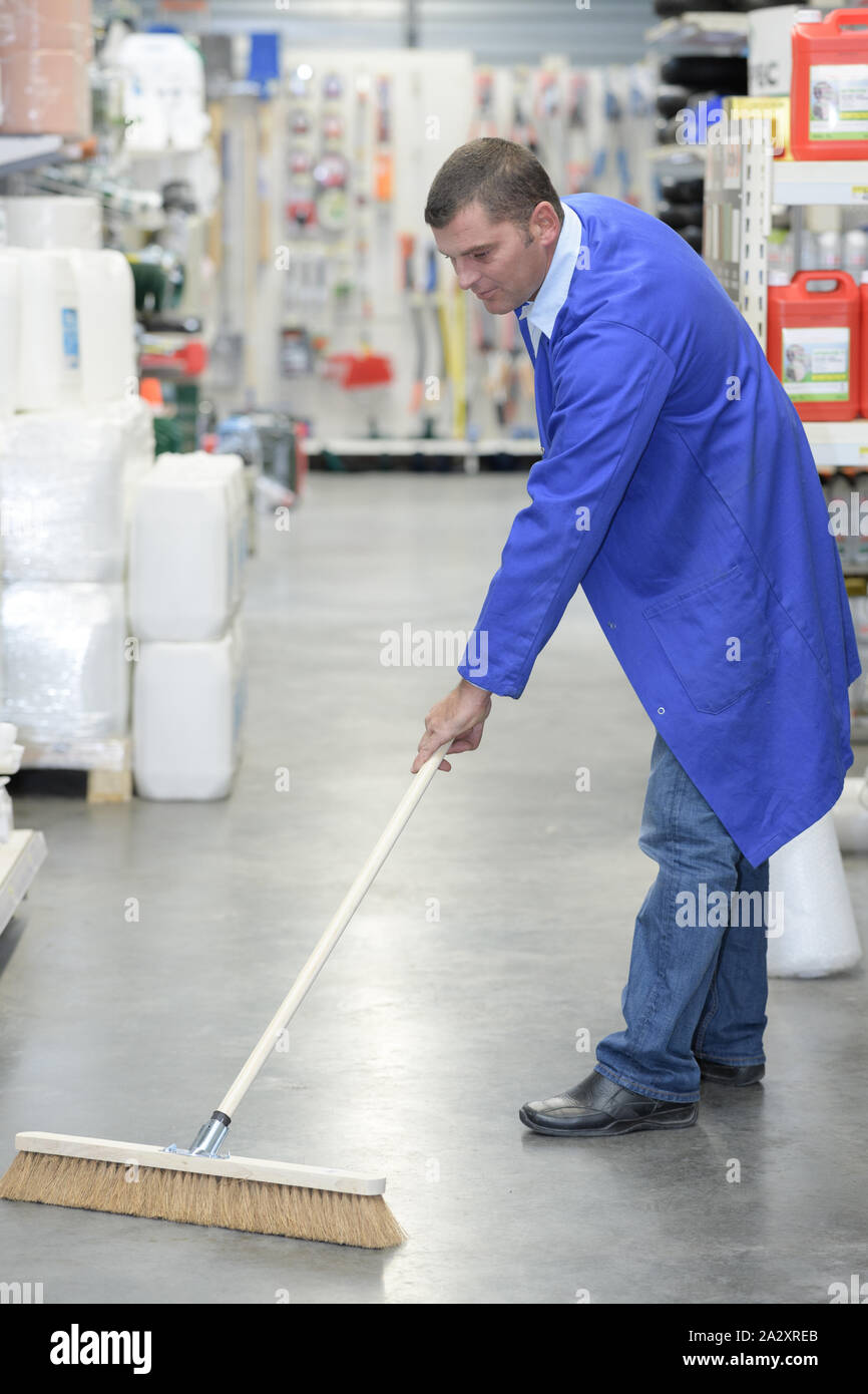 man sweeping floor of hardware center Stock Photo