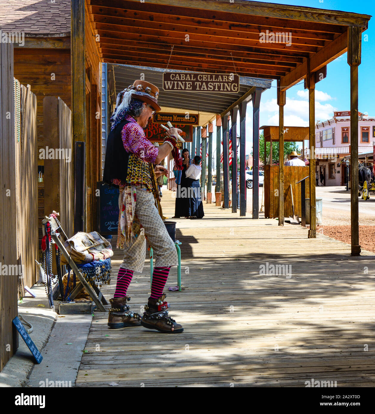 An eccentric performing artist, dressed wildly and using bone castanets dances for tips from tourists along the storefronts in Tombstone, AZ, USA Stock Photo