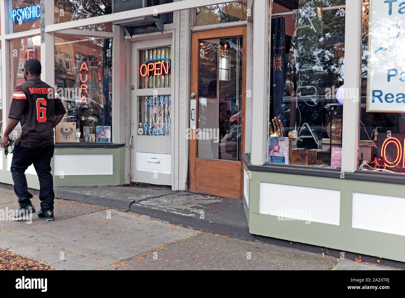 A Browns Football fan with a Mayfield jersy on walks past a psychic shop in downtown Cleveland, Ohio, USA. Stock Photo