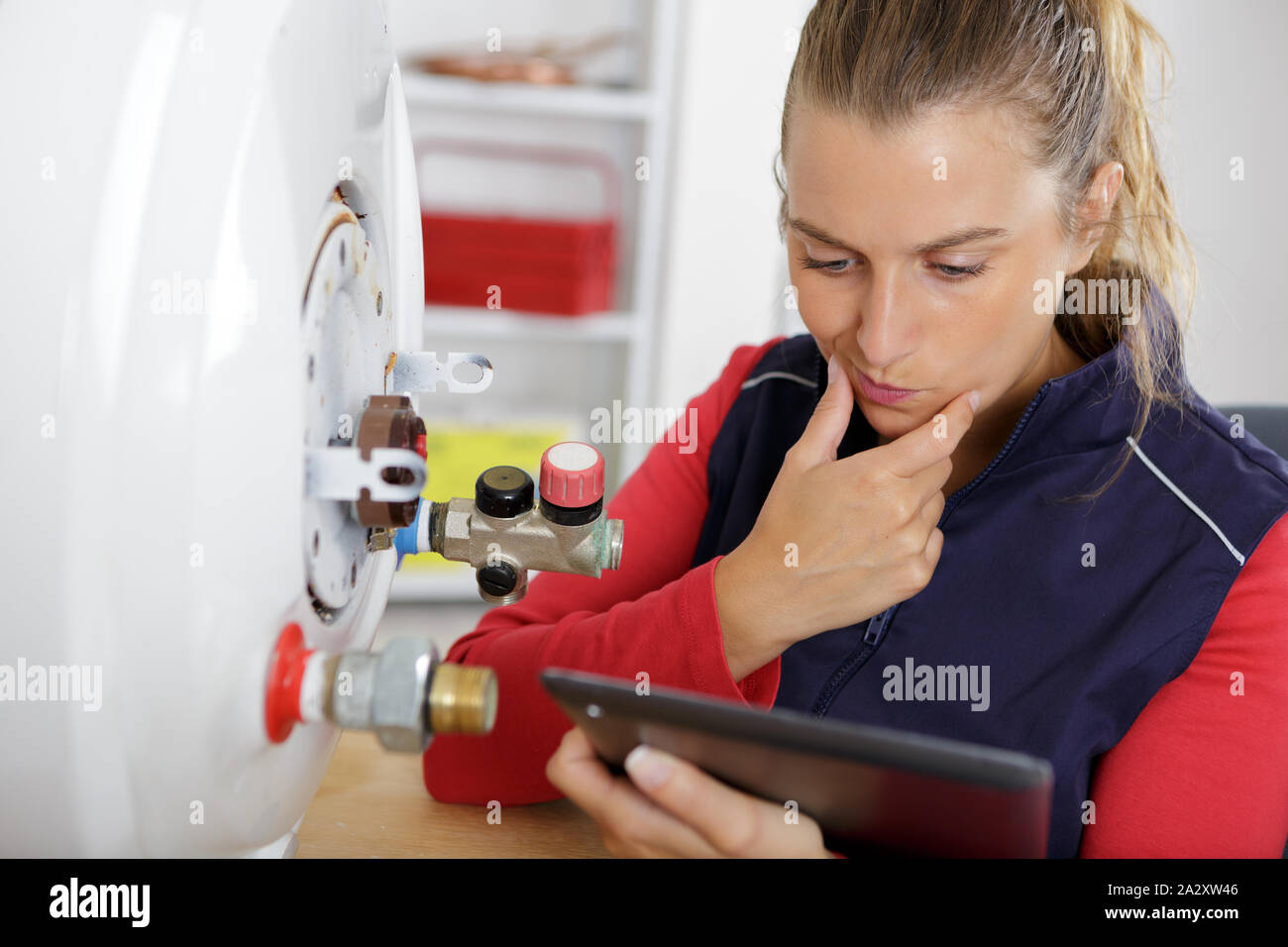 female technician servicing a boiler using tablet computer Stock Photo