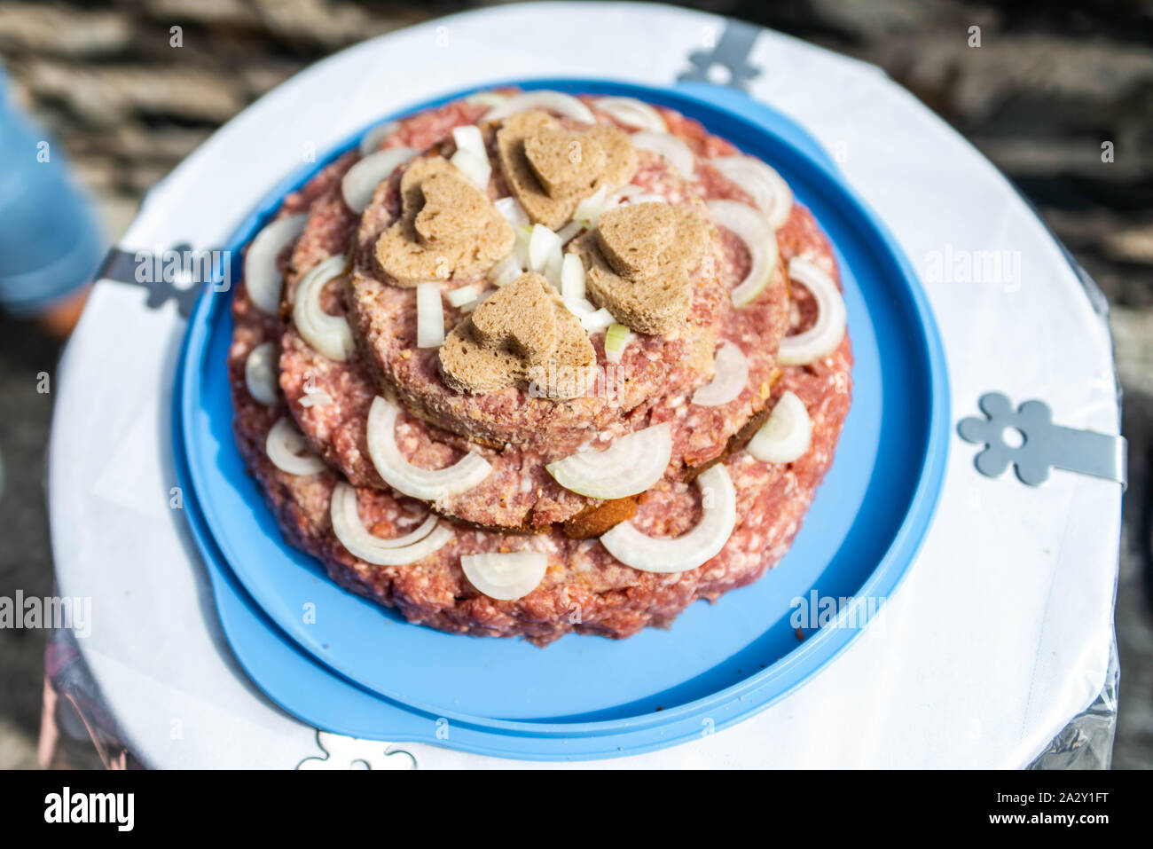 Wedding Cake raw Atriaux ground pork cuisine burgers on a slate tray with onion, rosemary, peppercorns and salt, served on a wedding close-up Stock Photo