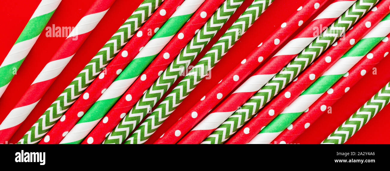 Striped drink straws on red background. Horizontal banner for web. New Year or Xmas pattern. Minimalism concept. Pop art style. Top view, Flat lay Stock Photo