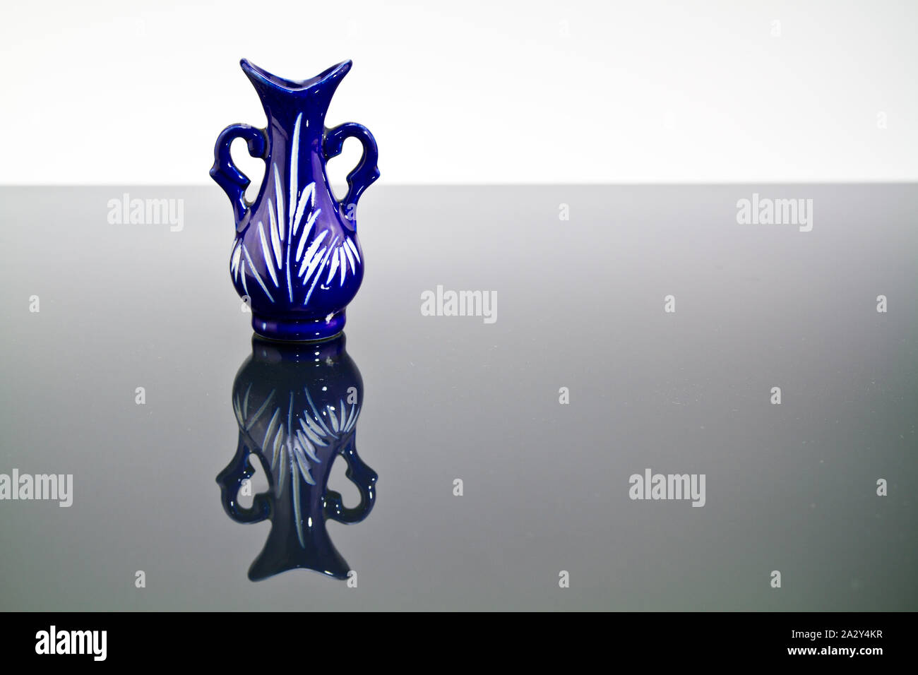 blue little vase on reflective surface and white background Stock Photo