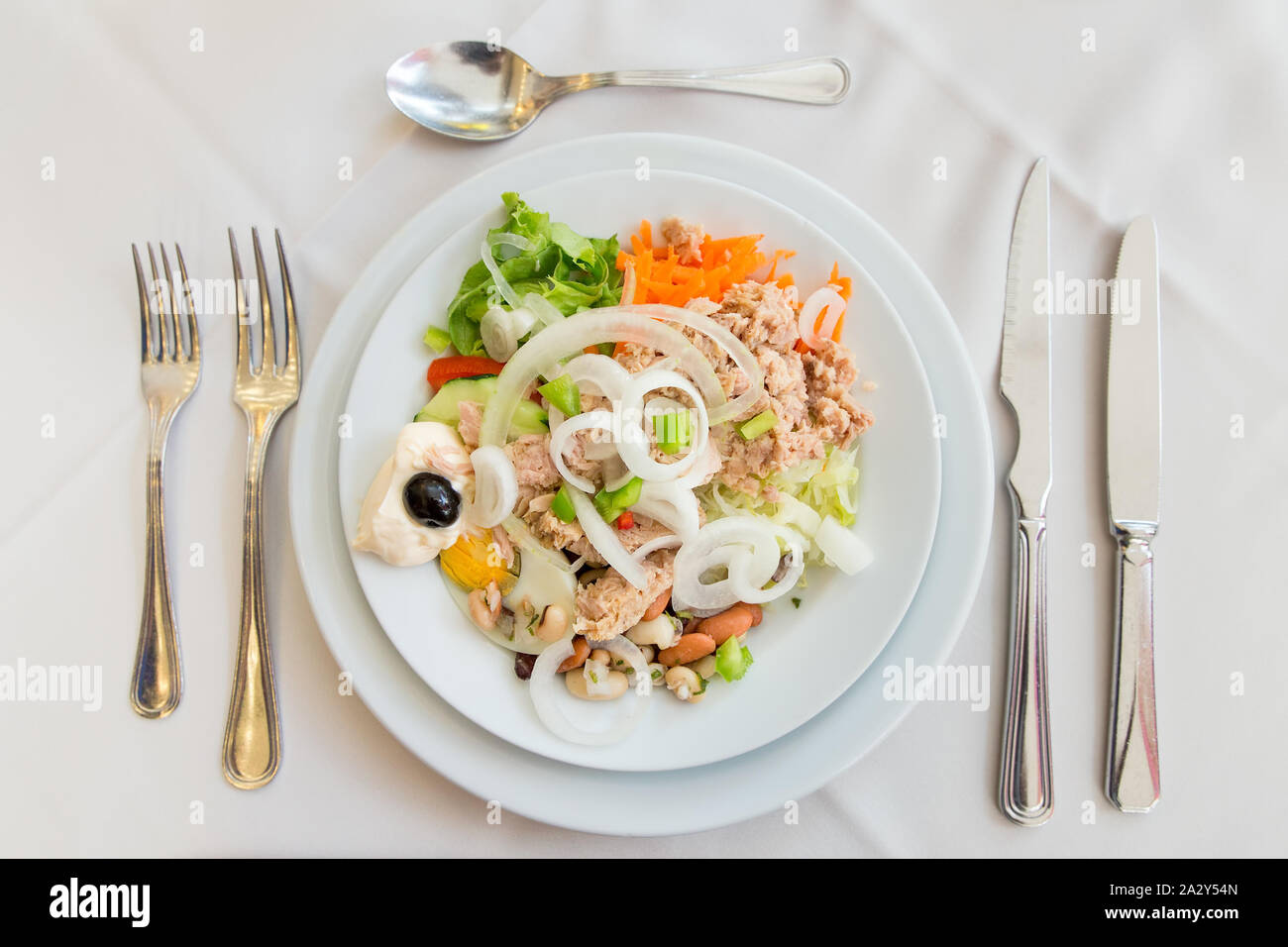 Plate with fresh salad on set table with garnish Stock Photo